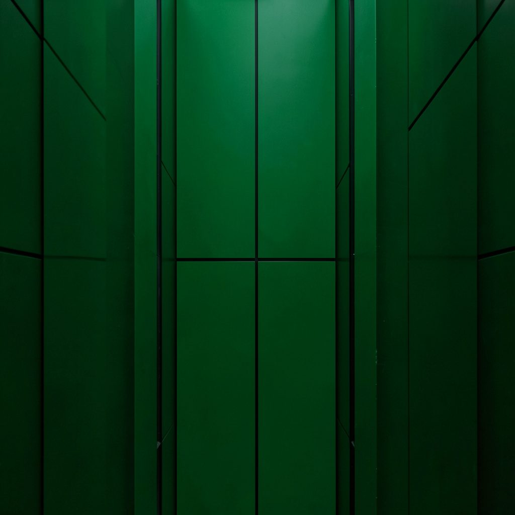 Dark emerald-toned casino interior with deep green felt tables, warm pendant lighting, and symmetrical rows of slot machines stretching into the background