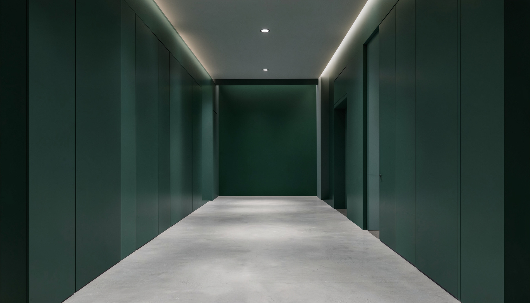 Symmetrical architectural interior with muted emerald and slate tones, soft ambient lighting, and clean geometric lines forming a balanced corridor view